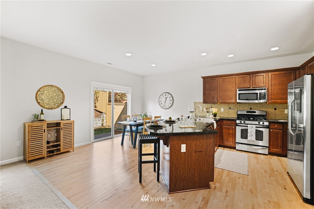 3007 182nd Place Southeast Bothell, WA 98012 - Photo 12 of 33 a kitchen with stainless steel appliances granite countertop a stove top oven a sink a dining table and chairs with wooden floor