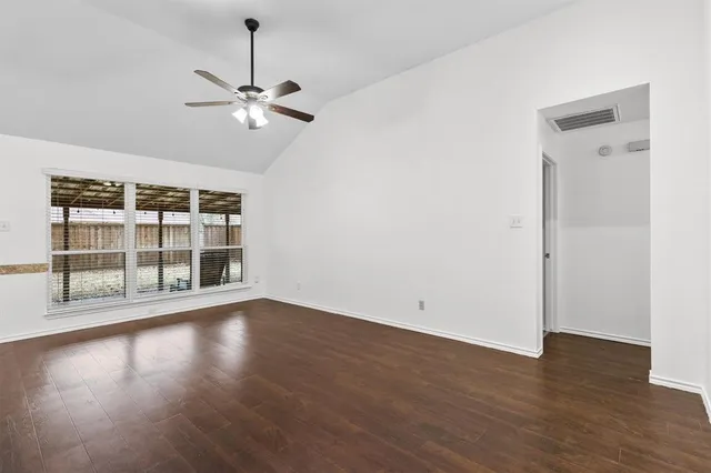 a view of empty room with wooden floor and fan