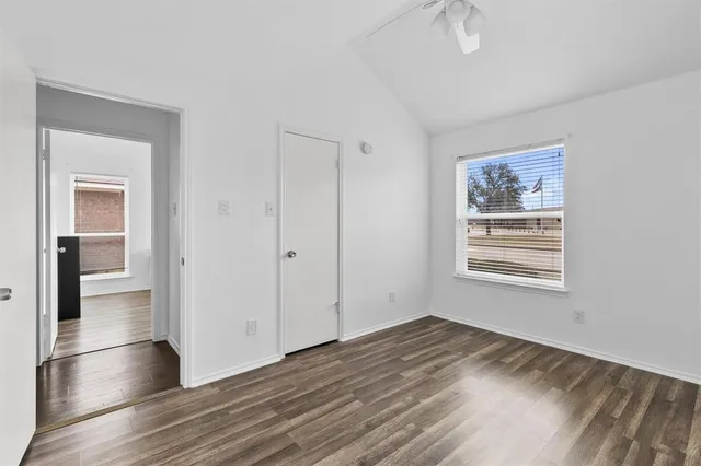a view of an empty room with window and wooden floor