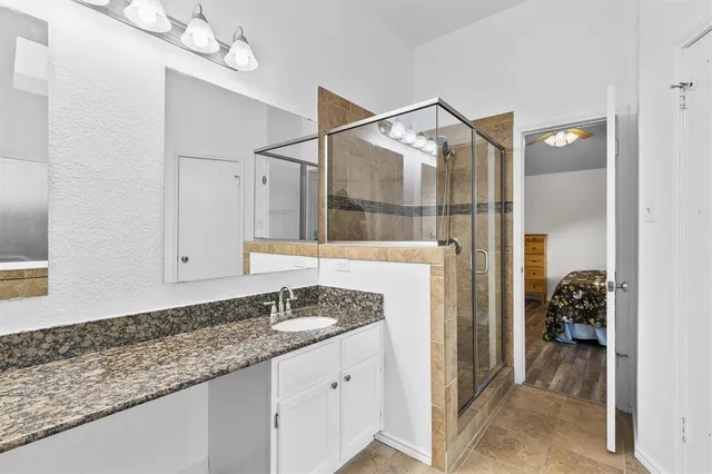 a bathroom with a granite countertop sink a mirror and shower