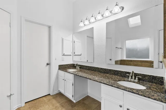 a bathroom with a granite countertop double vanity sink and mirror