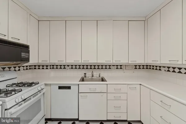 a kitchen with granite countertop white cabinets and a stove