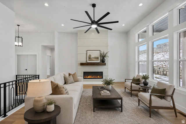710 East Mountain Road North Ogden, UT 84414 - Photo 22 of 36 Living area featuring a floor-to-ceiling fireplace with a wood mantle and linear electric insert, expansive windows, wood-finish flooring, and a contemporary ceiling fan