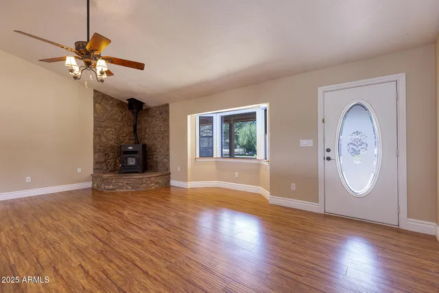 a view of an empty room with wooden floor and fan