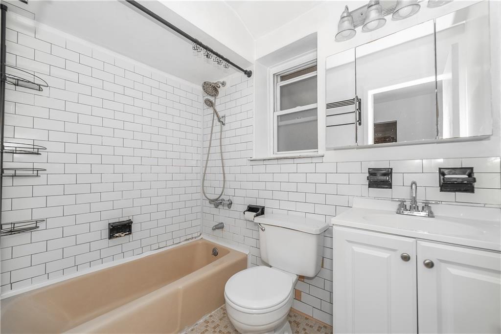2963 Ocean Parkway, Unit 3F Brooklyn, NY 11235 - Photo 5 of 16 a bathroom with a bathtub shower sink mirror vanity and toilet