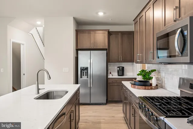 a kitchen with stainless steel appliances a sink a stove a refrigerator cabinets and a counter top space