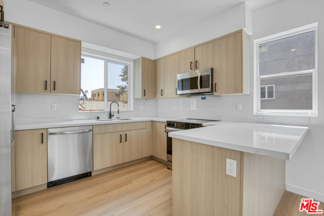 10828 Hesby Street North Hollywood, CA 91601 - Photo 14 of 33 a kitchen with stainless steel appliances granite countertop a sink stove and microwave