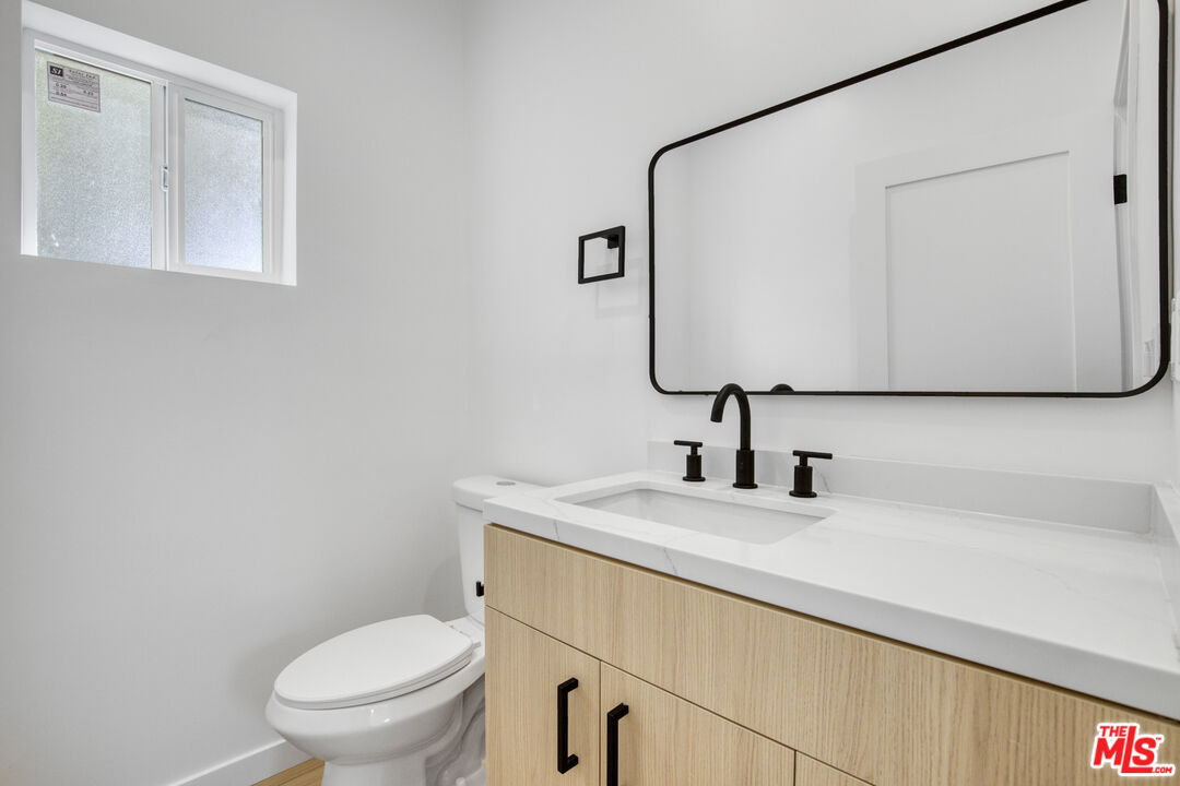 10828 Hesby Street North Hollywood, CA 91601 - Photo 29 of 33 a bathroom with a toilet sink and mirror