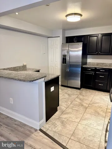 a kitchen with granite countertop a stove a sink and a refrigerator