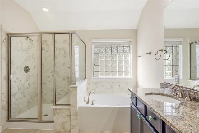 a bathroom with a granite countertop sink a large mirror and a bathtub