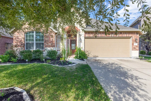 a front view of a house with garden and trees