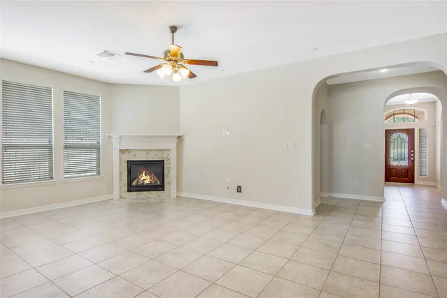 a view of a livingroom with a fireplace a chandelier fan and windows