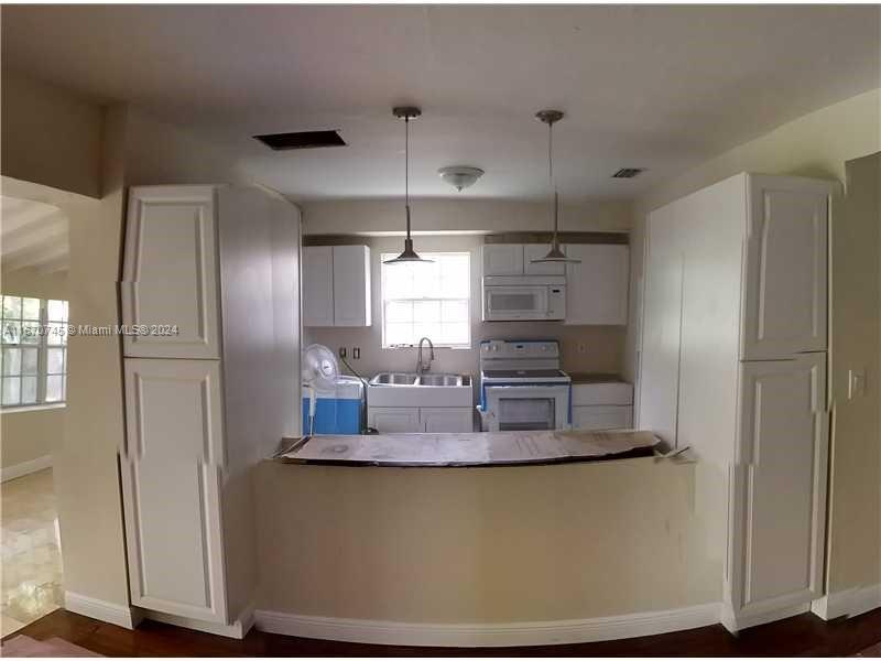 2424 Southwest 21st Street Miami, FL 33145 - Photo 2 of 9 a kitchen with kitchen island a refrigerator a stove a sink and a window