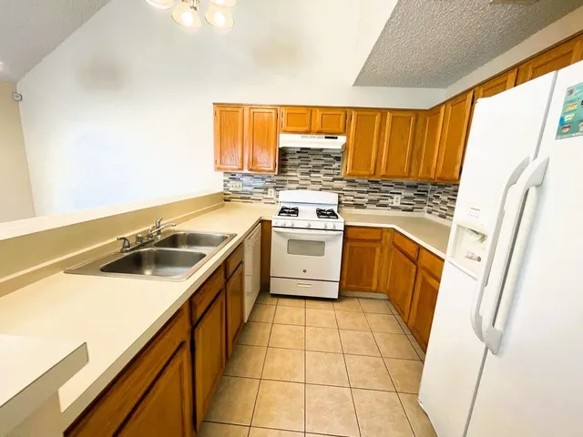 a kitchen with a sink a stove top oven and a refrigerator