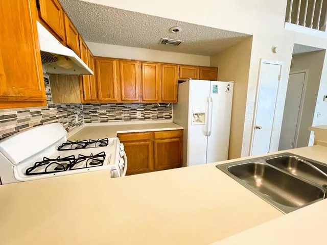 a kitchen with granite countertop a stove a refrigerator and a stove with wooden floor