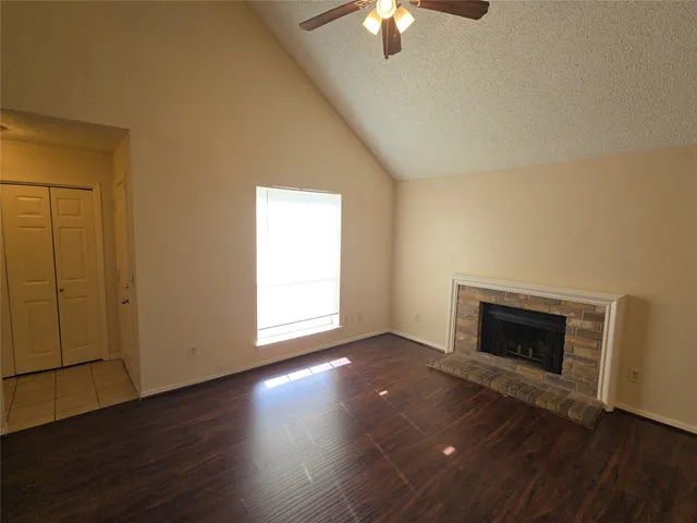 an empty room with wooden floor fireplace and windows