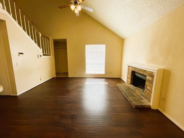 a view of a livingroom with wooden floor a fireplace and windows