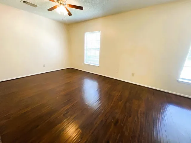 an empty room with wooden floor and windows