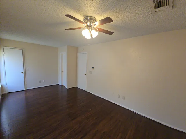 an empty room with wooden floor and fan