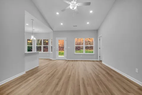 a view of an empty room with a window and wooden floor