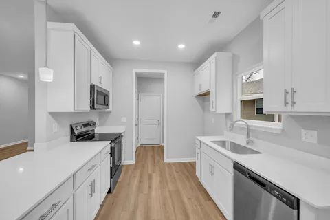 a kitchen with a sink a counter top space stainless steel appliances and cabinets