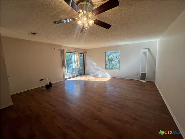 a view of an empty room with window and wooden floor