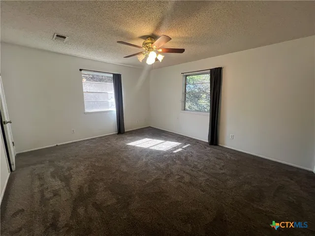 an empty room with windows and fan
