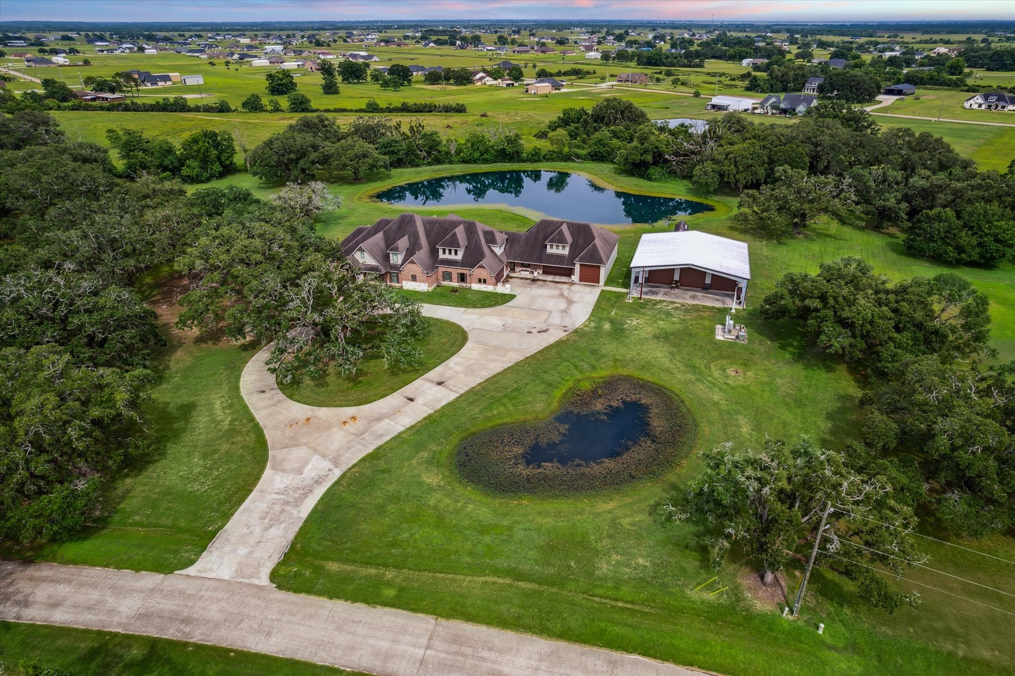 1255 Bronco Trail Angleton, TX 77515 - Photo 44 of 50 Nestled on 5 acres, this custom two-story home is set against a stunning backdrop of nature. A spacious, circle concrete driveway enhances the home's curb appeal, providing easy access and plenty of room for parking. The expansive lot offers both privacy and endless possibilities for outdoor living.