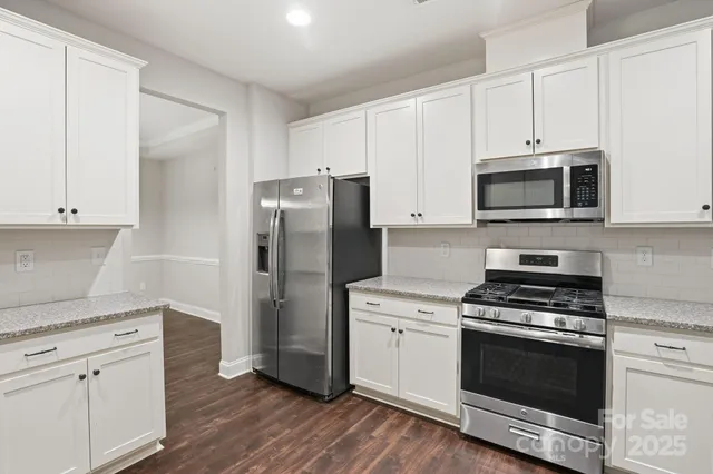 a kitchen with cabinets stainless steel appliances and wooden floor