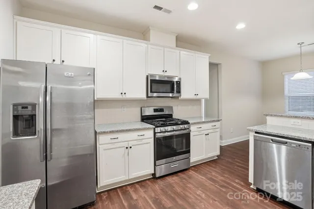 a kitchen with stainless steel appliances granite countertop a refrigerator stove and sink