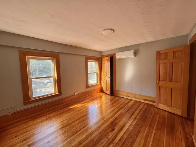 a view of an empty room with window and wooden floor