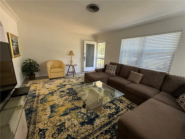 a living room with furniture a flat screen tv and a window