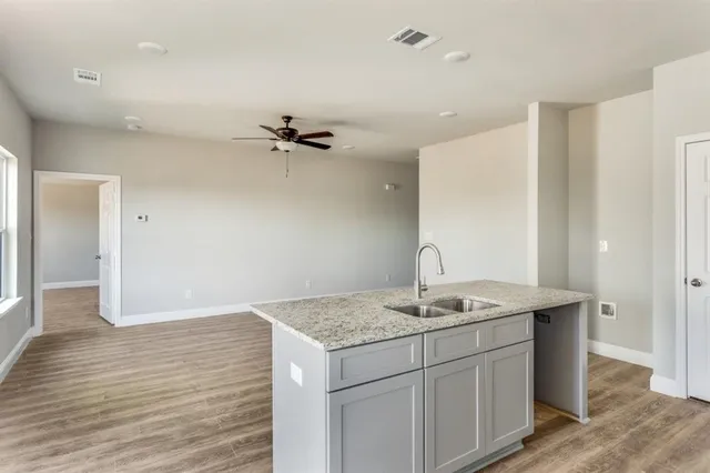 a kitchen with granite countertop a sink a stove and cabinets