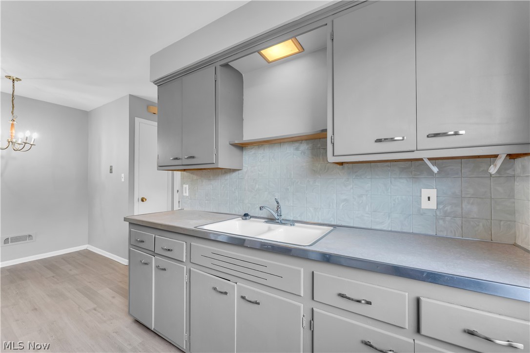2915 Snow Road, Unit 2/UP Cleveland, OH 44134 - Photo 8 of 23 Kitchen area featuring light gray cabinetry with chrome hardware, an integrated double basin sink, and a light-toned tile backsplash