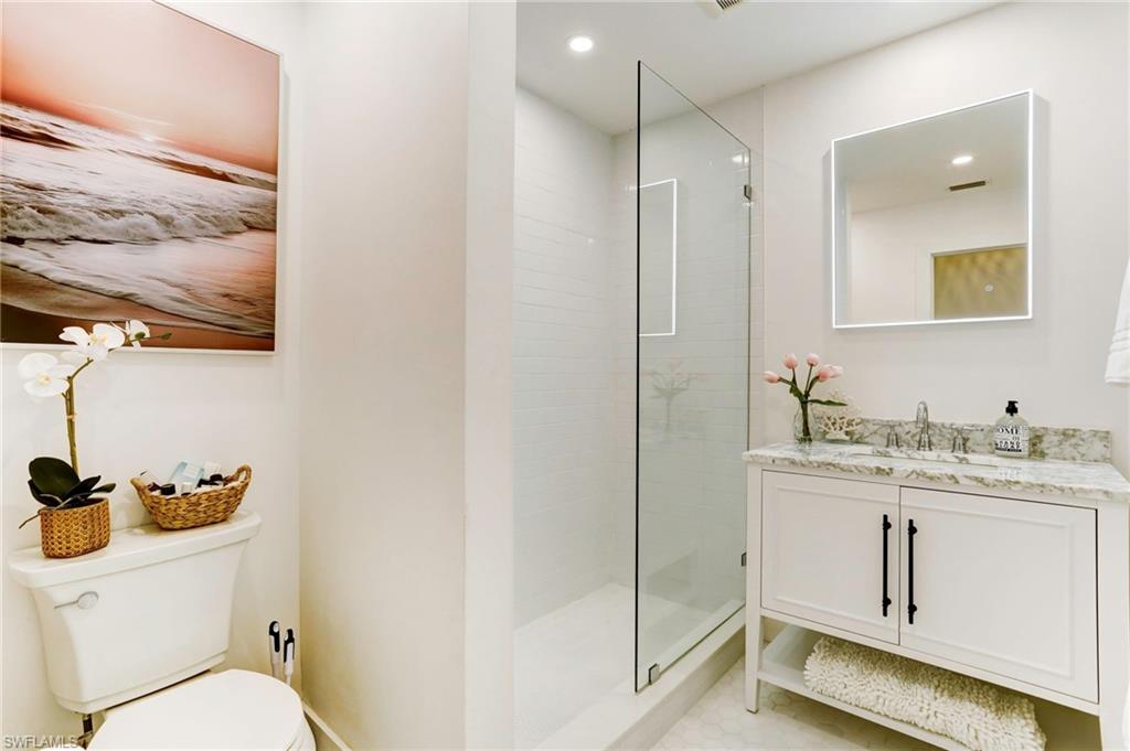 1793 Smugglers Cove, Unit B Naples, FL 34112 - Photo 15 of 24 a bathroom with a granite countertop sink a toilet a mirror and shower