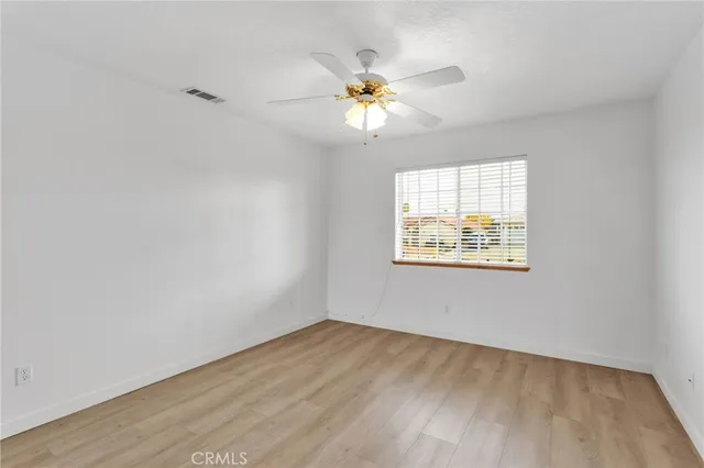 an empty room with wooden floor chandelier fan and windows