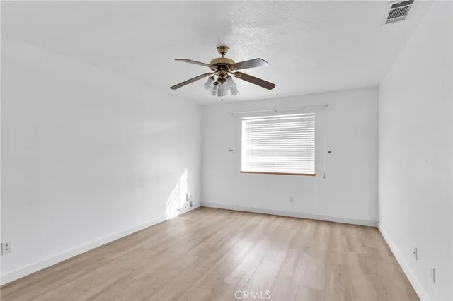 an empty room with a window and a ceiling fan