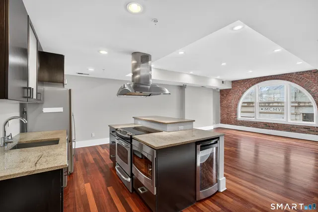 a kitchen with stainless steel appliances granite countertop a sink a stove and a wooden floors