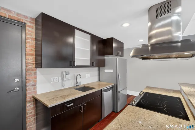 a kitchen with stainless steel appliances kitchen island granite countertop a refrigerator and a stove top oven