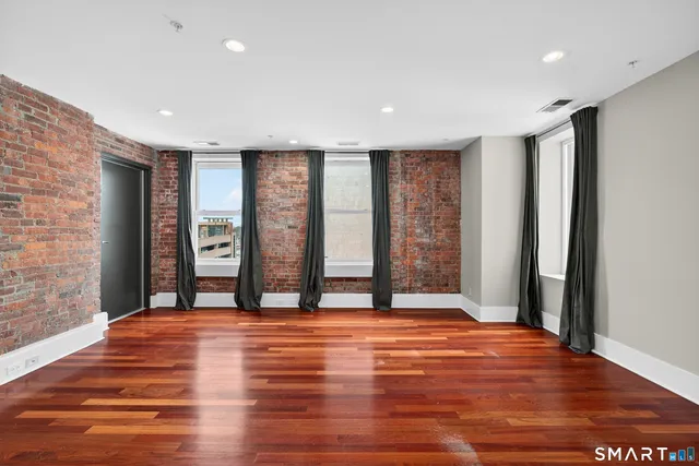 a spacious bedroom with a bed a dresser and a window