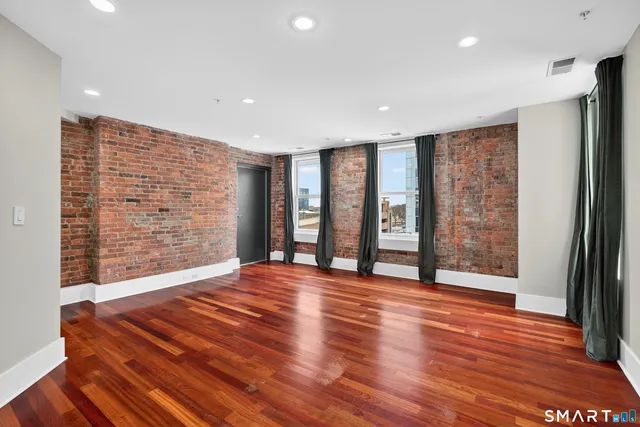 a view of an empty room with wooden floor and closet