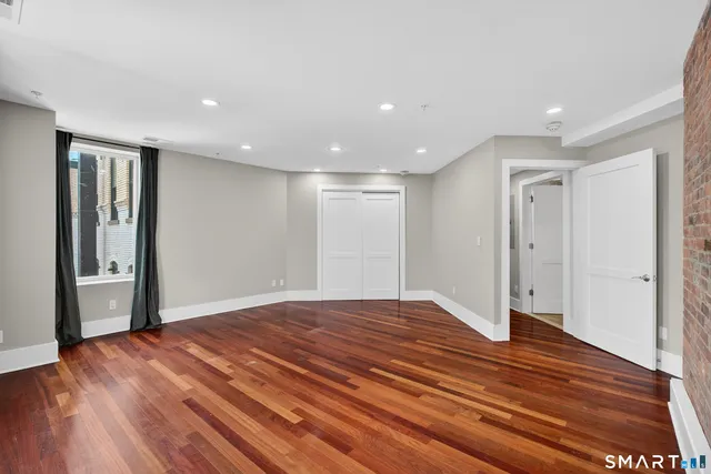 a view of an empty room with wooden floor and a window