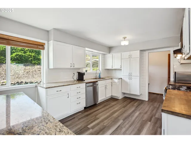 a kitchen with granite countertop white cabinets a appliances a sink and a counter space