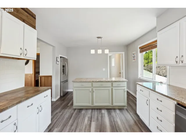 a large kitchen with a lot of counter space and wooden floor
