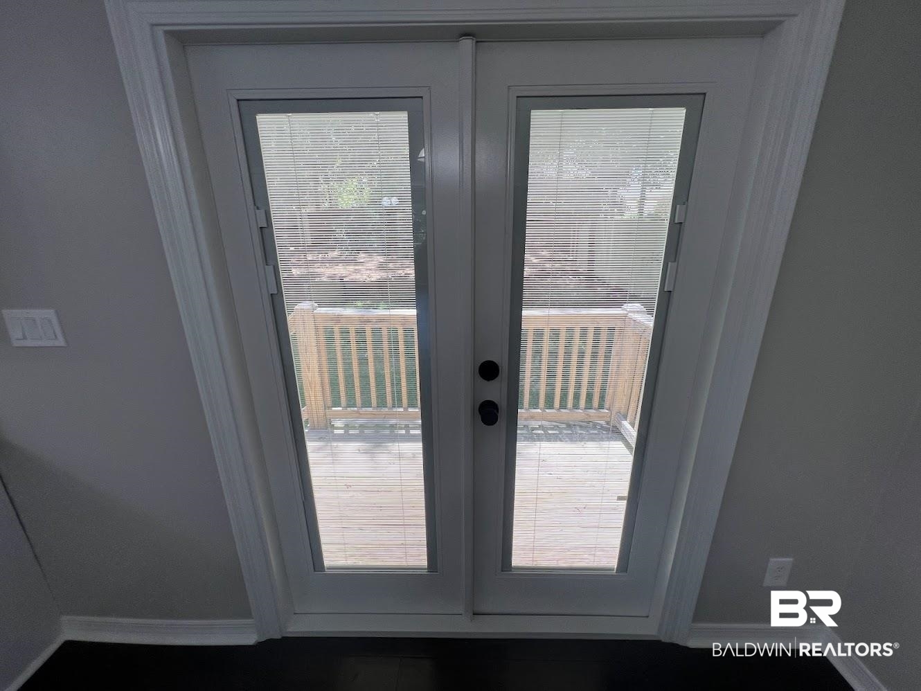 266 Ridgewood Drive Daphne, AL 36526 - Photo 7 of 34 Double patio doors with integrated blinds opening onto a wooden deck with railing
