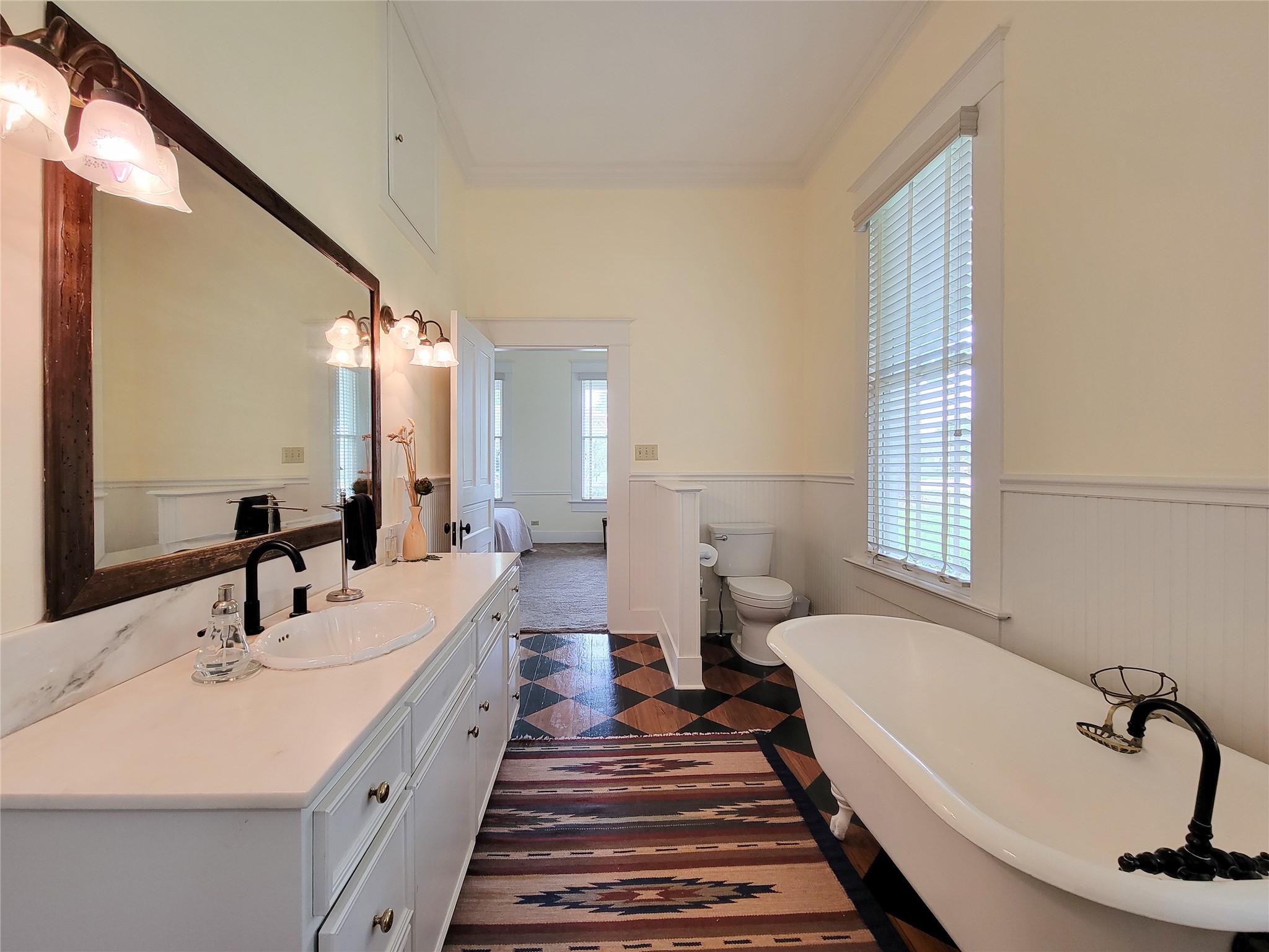 1406 Key Street Brenham, TX 77833 - Photo 18 of 50 Experience luxury in the primary en-suite with stunning antique hardwood floors, elegant double vanities, and a relaxing soaking tub.