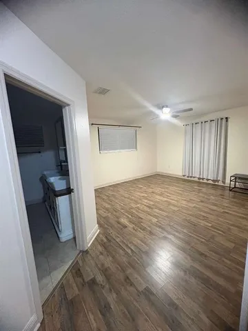 a view of an empty room with wooden floor and stairs