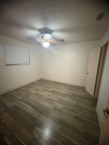 an empty room with wooden floor and fan