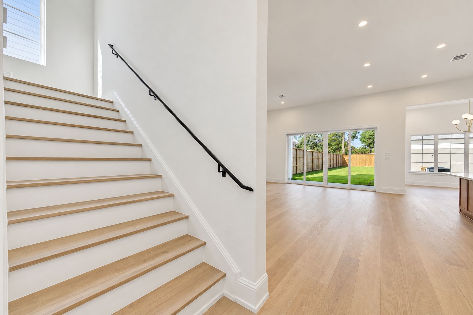 2309 Hollister Road Houston, TX 77080 - Photo 18 of 47 A beautifully designed staircase creates a seamless transition between levels, pairing warm wood treads with crisp contemporary detailing and a sleek handrail. Positioned alongside the light-filled living spaces, the open stairway enhances the home’s airy architectural flow while maintaining a refined, modern aesthetic.