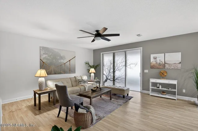 a living room with furniture a wooden floor and a ceiling fan